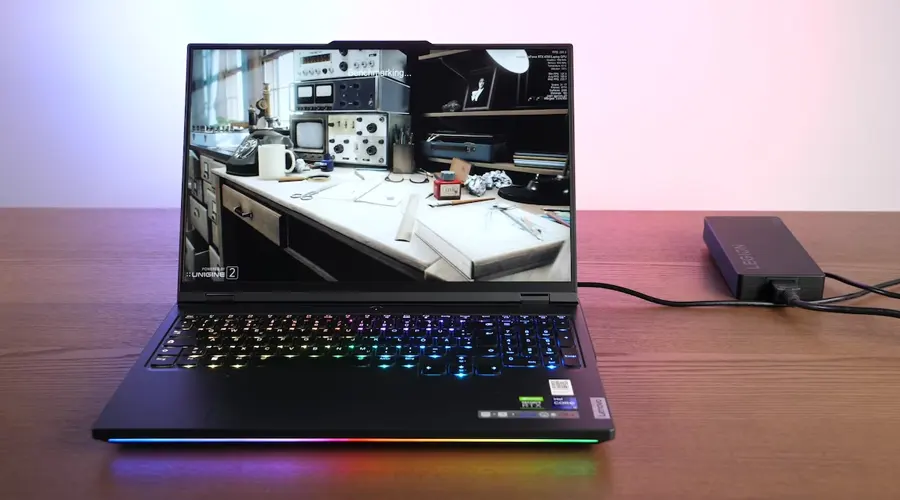 نمایش بازی کامیپوتری بر روی صفحه نمایش لپ تاپ مدل Legion 7 Pro متصل به شارژر روی میز چوبی