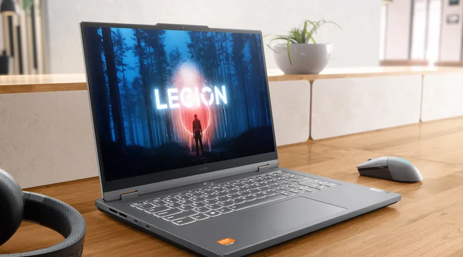 لپ تاپ گیمینگ لنوو با کیبورد طوسی روی میز چوبی در کنار گلدان با نمایش LEGION بر روی صفحه